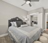 Cozy bedroom with gray bedding, decorative pillows, a black headboard, ottomans at the foot, and an open closet.