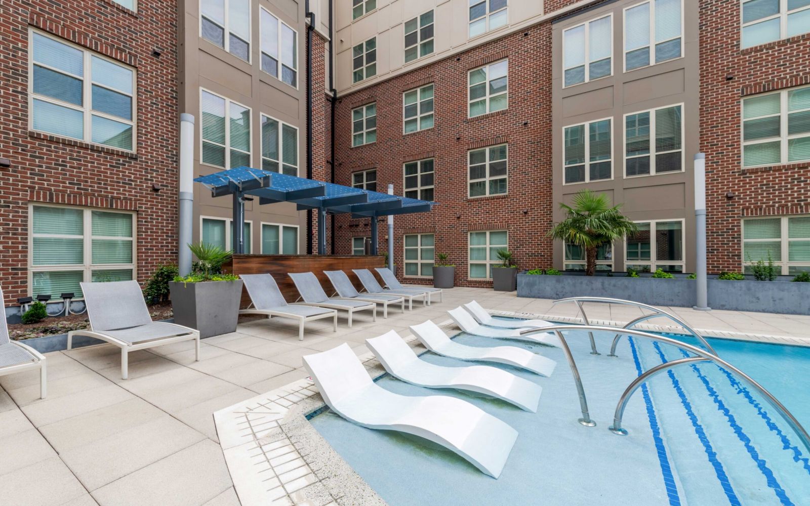 Modern apartment courtyard at Carolina Square with pool, lounge chairs, and shaded seating—ideal for UNC sophomores seeking on-campus housing.