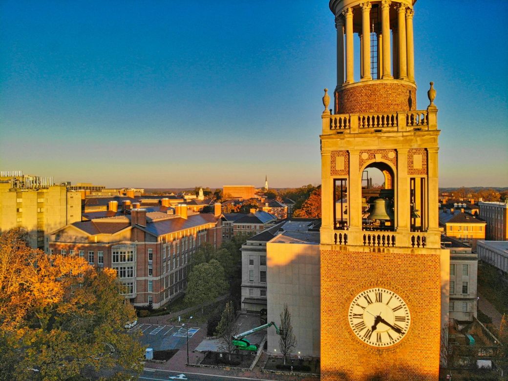 Bell tower with a clock at sunset, overlooking campus and trees, near Downtown Chapel Hill dining and vibrant Chapel Hill restaurants.