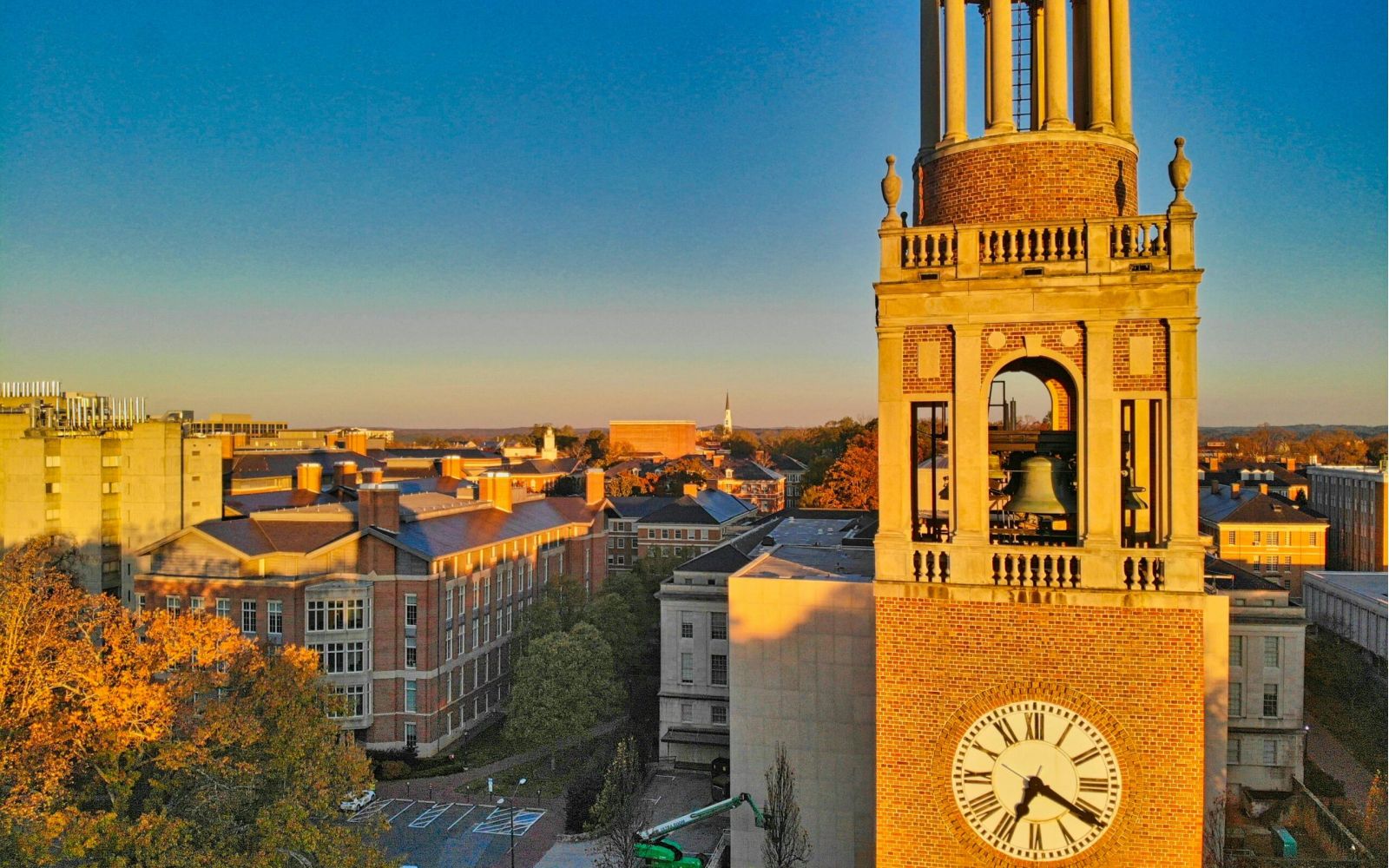 Bell tower with a clock at sunset, overlooking campus and trees, near Downtown Chapel Hill dining and vibrant Chapel Hill restaurants.