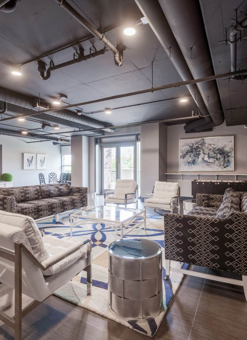 Modern lounge with patterned chairs, white armchairs, artwork, a pool table, and large windows.