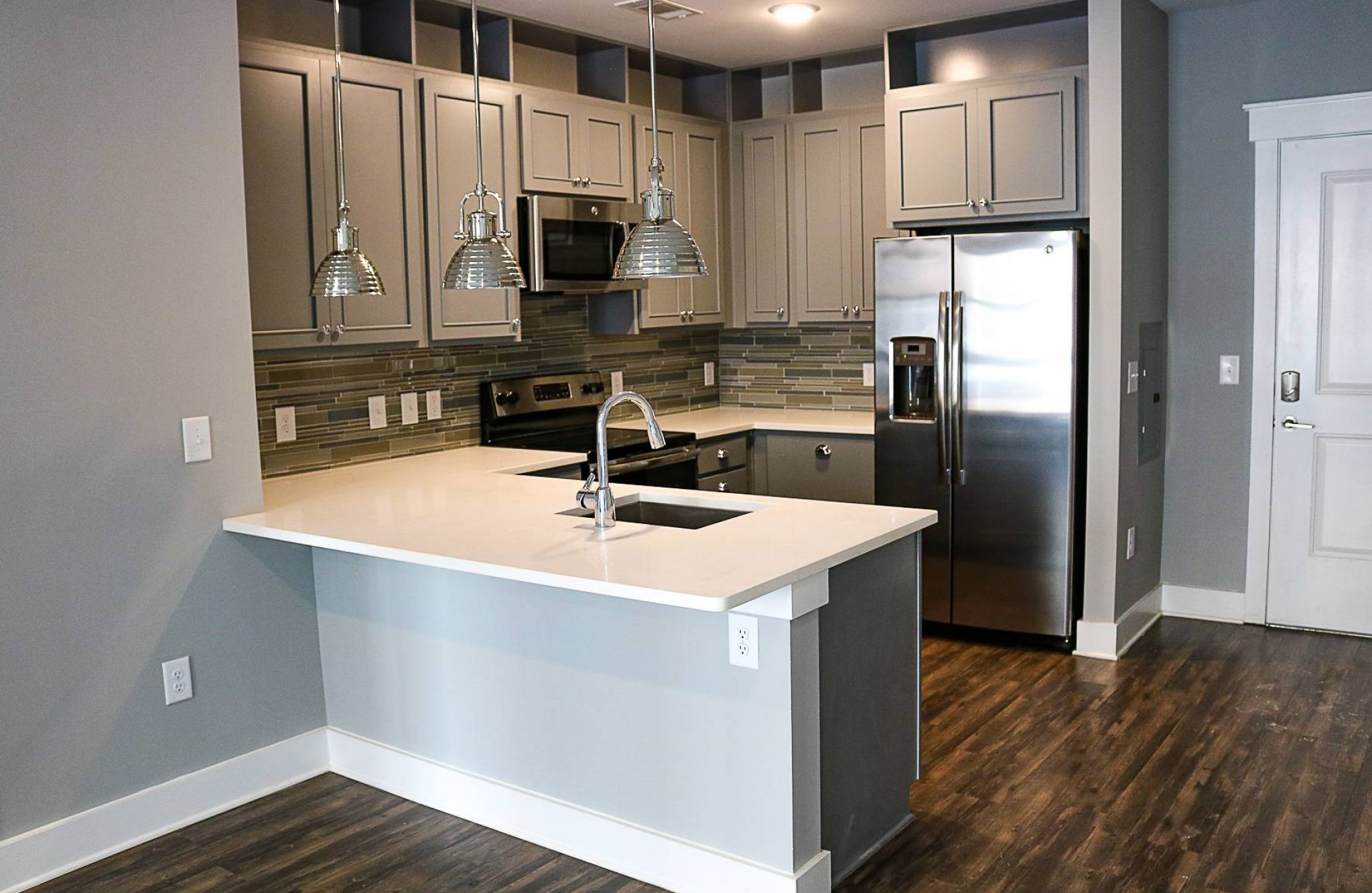 Studio apartment kitchen with stainless steel appliances, built-in wine storage, and small dining table