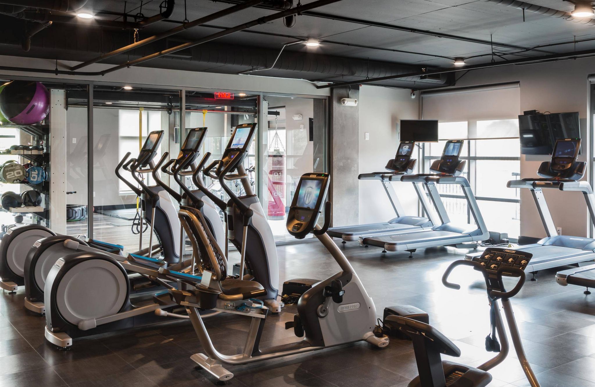 Modern gym with treadmills, elliptical machines, and cardio equipment in a bright, spacious room.