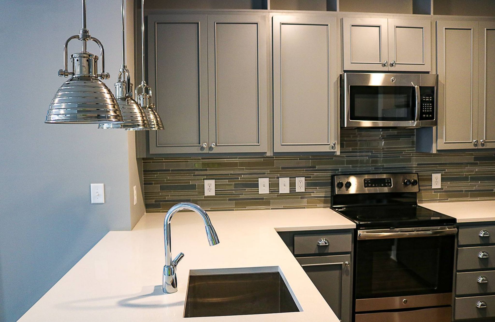 Luxury apartment kitchen with floating kitchen island, pendant lighting, ample cabinet storage, and built-in wine storage
