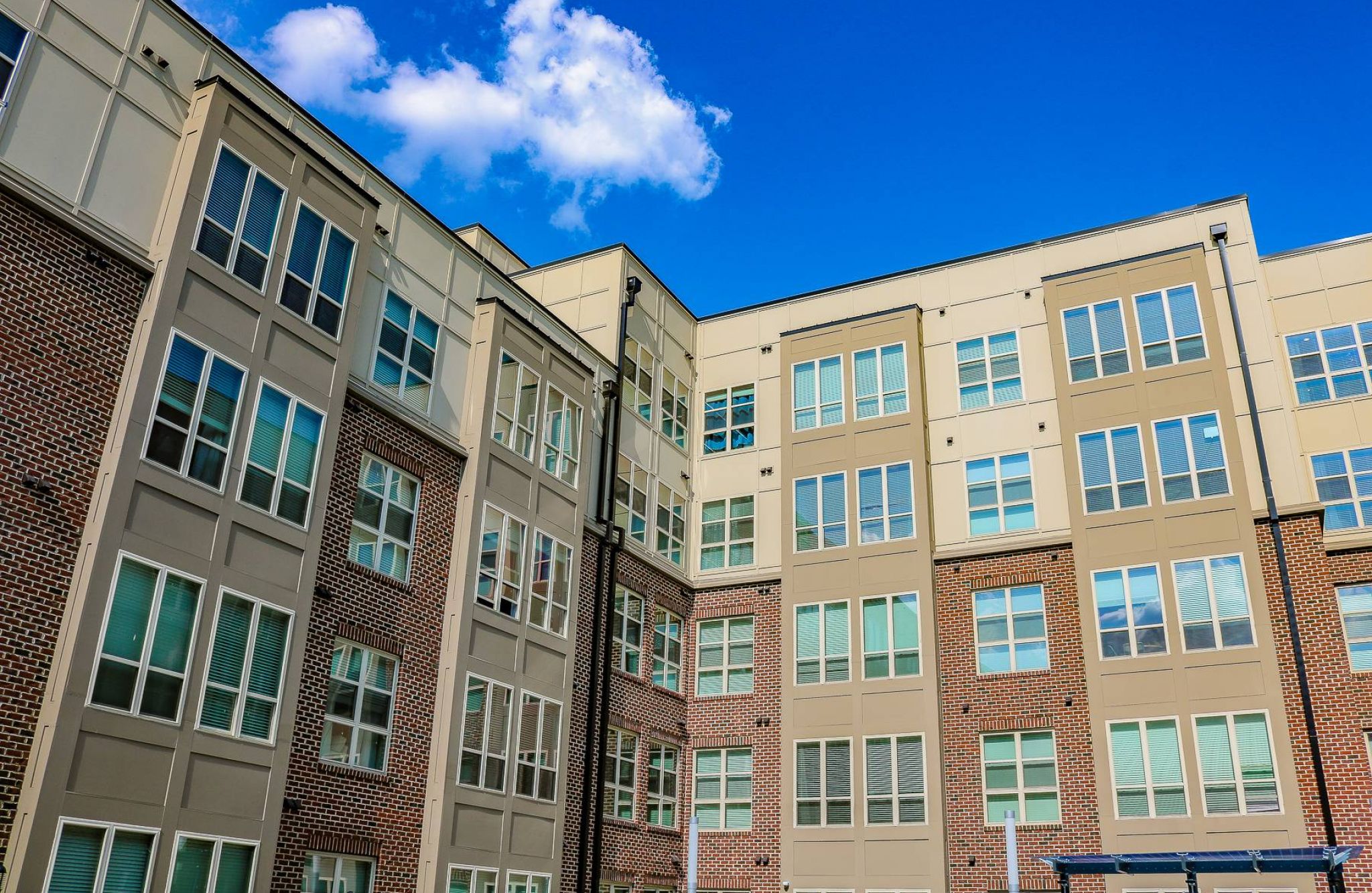 Modern apartment building with large windows against a bright blue sky with a few clouds.