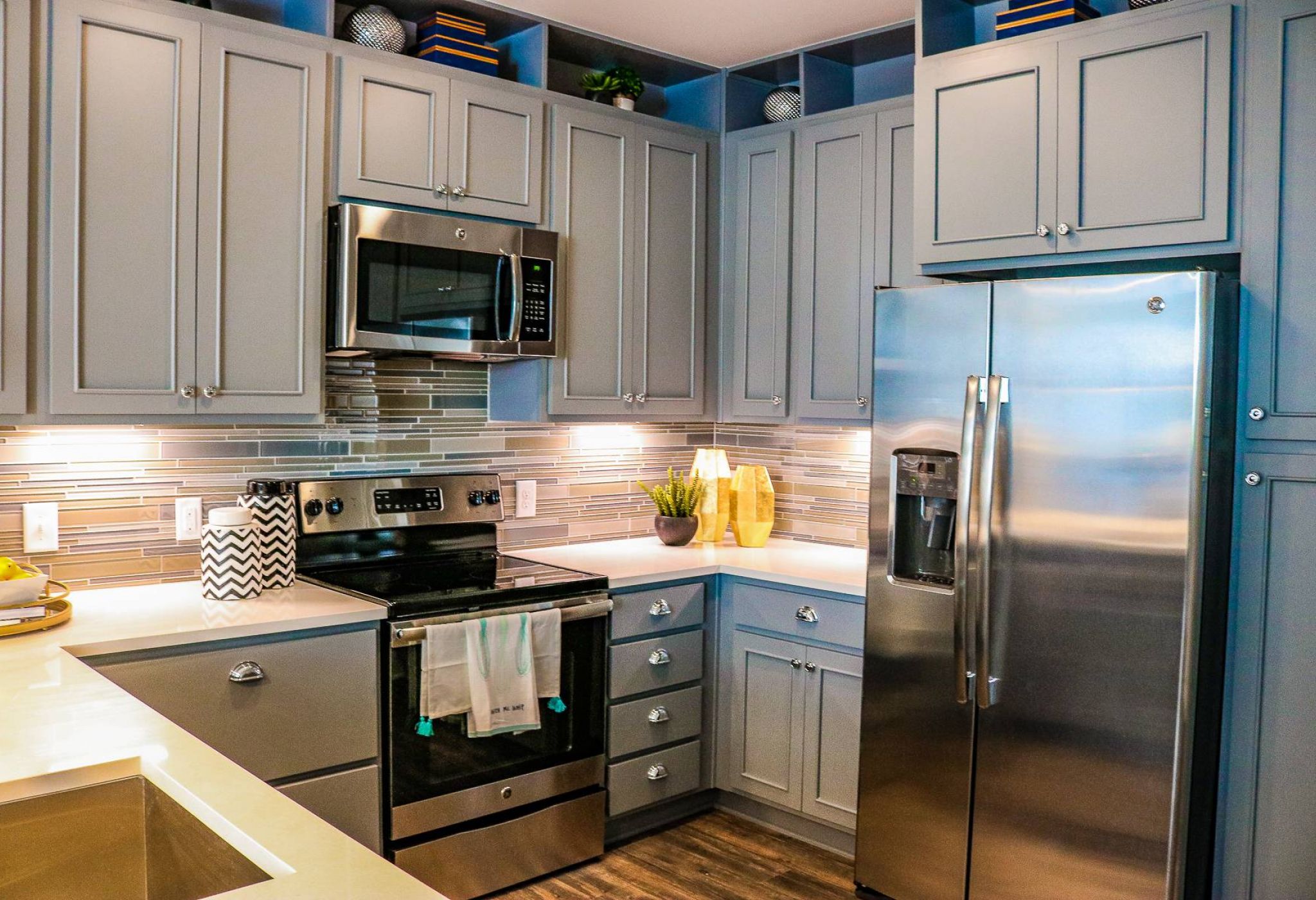 Modern kitchen with grey cabinets, stainless steel appliances, and a tile backsplash above the stove.