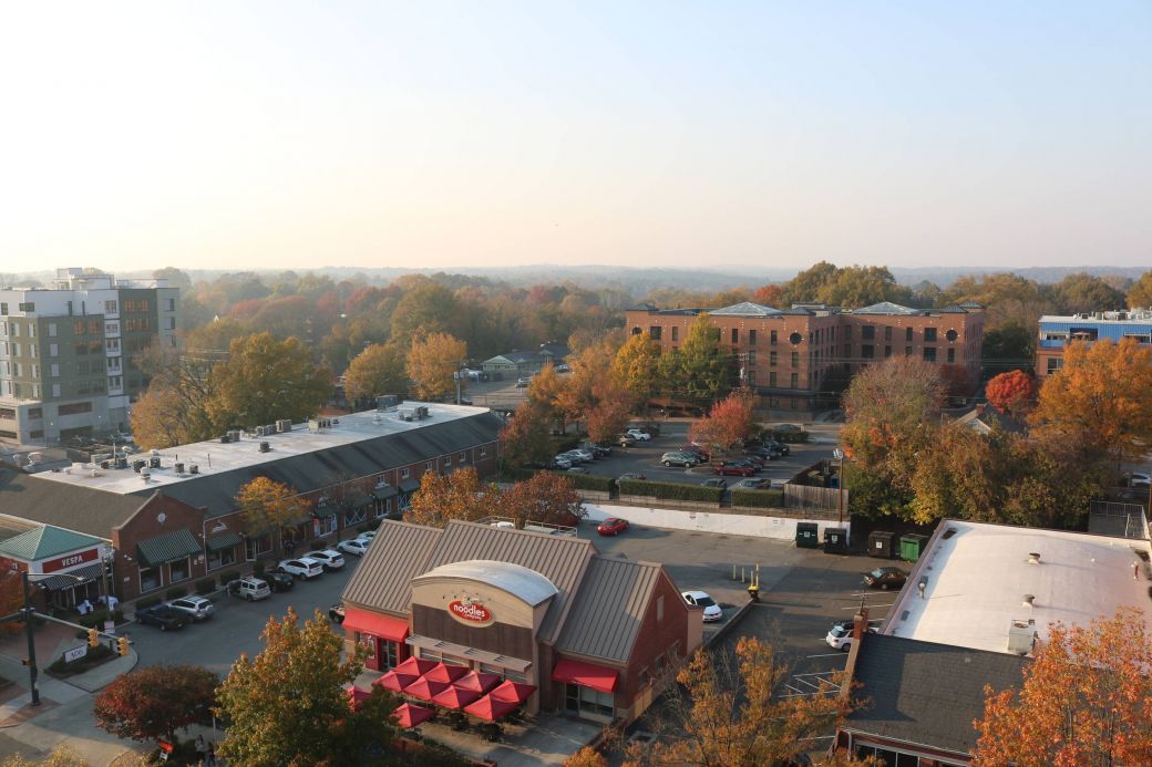 Aerial view of a small town with autumn trees, shops, and red awnings on a clear day.