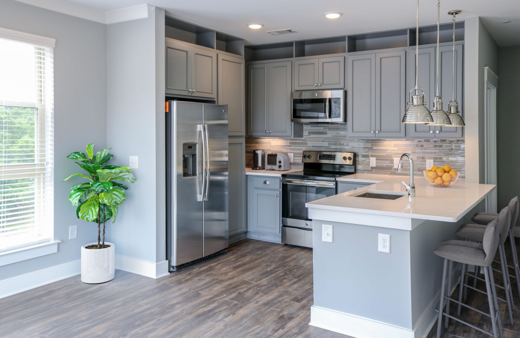 Luxury apartment kitchen with floating kitchen island, pendant lighting, ample cabinet storage, and built-in wine storage