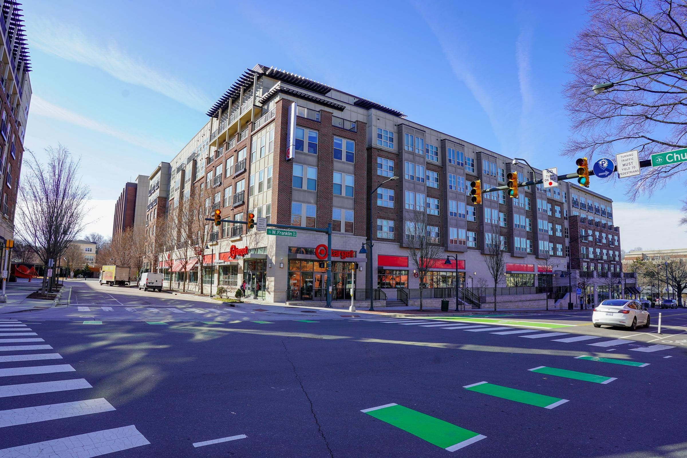 A city intersection with crosswalks, a Target store, and apartments above under a clear blue sky at Carolina Square aparements