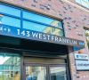 Modern brick apartment building entrance with a sign reading “143 West Franklin” above glass doors.
