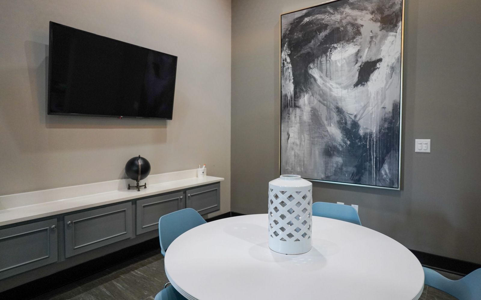 Round table with blue chairs, modern decor, and abstract art—perfect for a student home near UNC-Chapel Hill in Carolina Square.