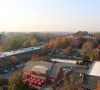 Aerial view of a small town with autumn trees, shops, and red awnings on a clear day.