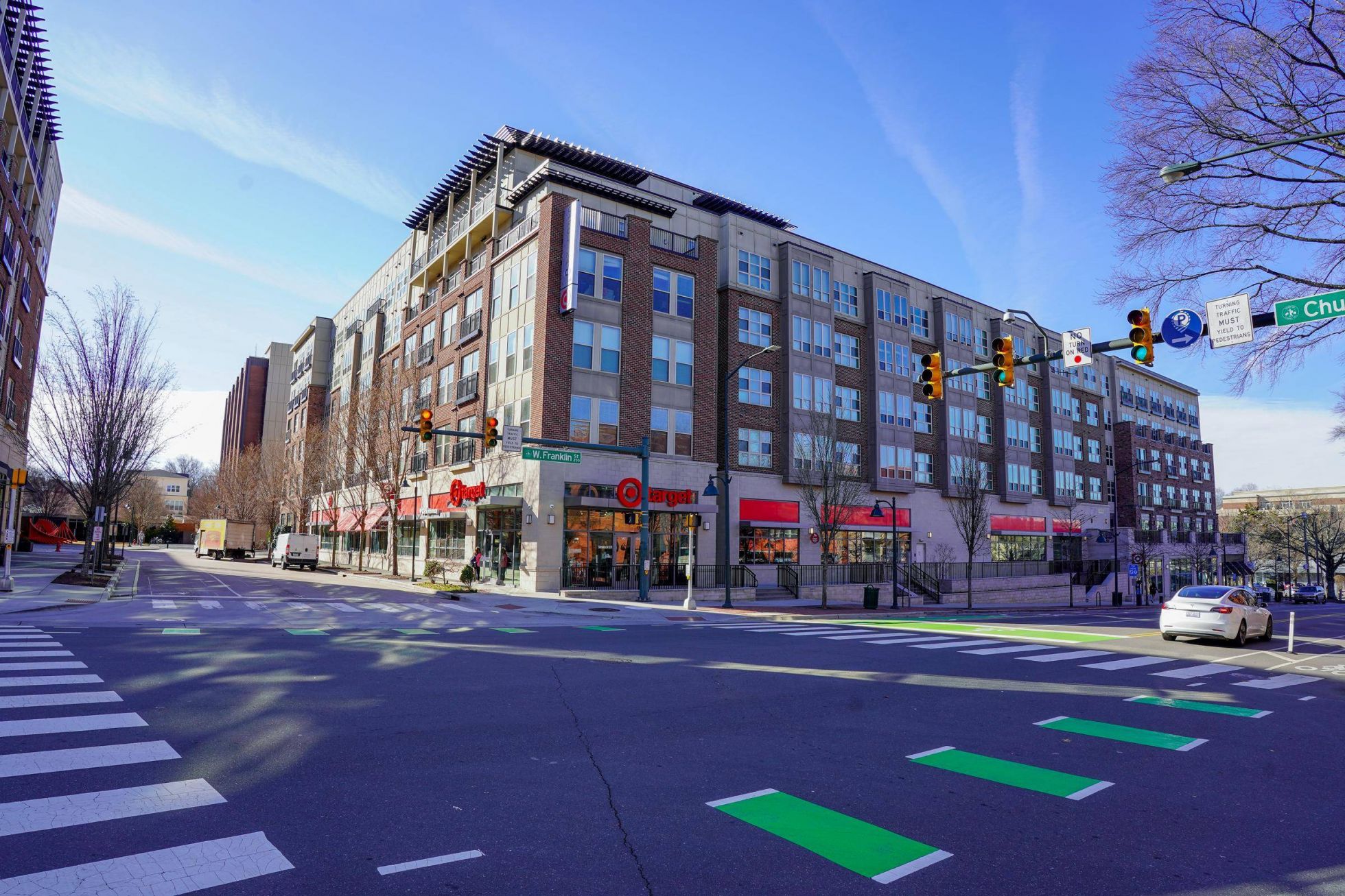 A city intersection with crosswalks, a Target store, and apartments above under a clear blue sky at Carolina Square aparements