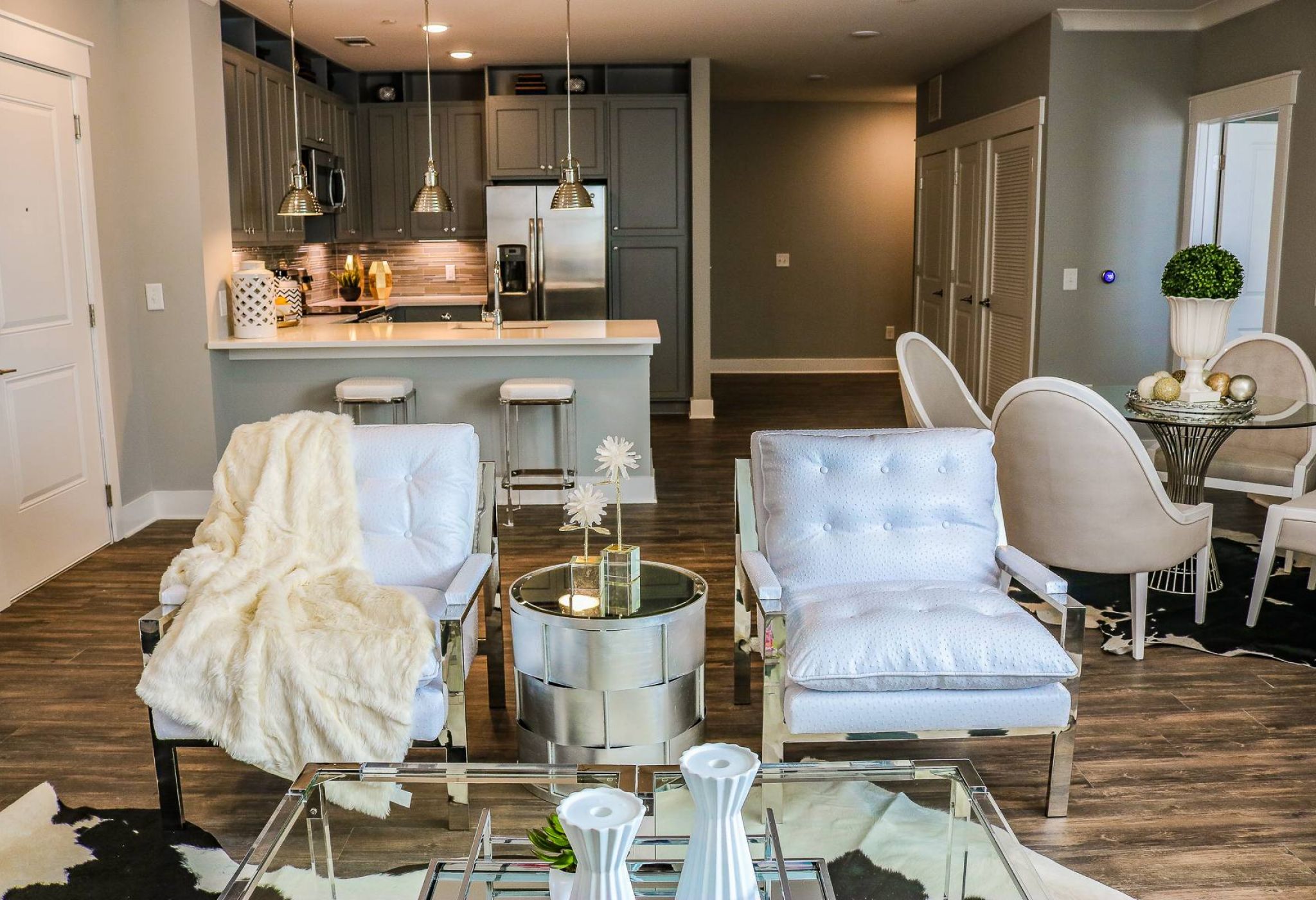 Modern living room with white chairs, a kitchen island in the background, and stylish decor throughout.