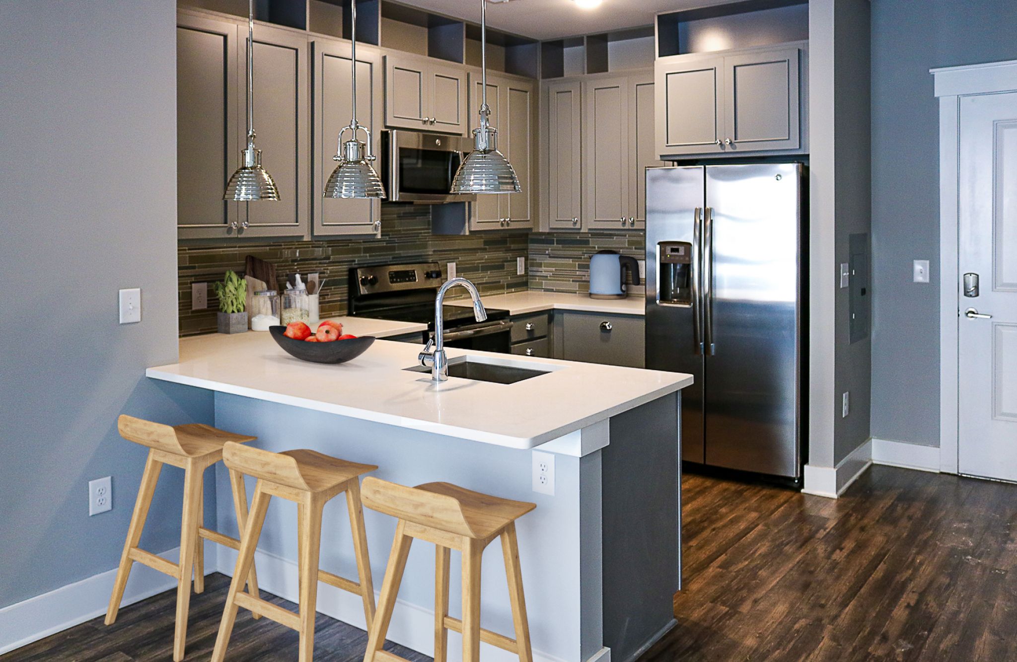 Studio apartment kitchen with stainless steel appliances, built-in wine storage, and small dining table