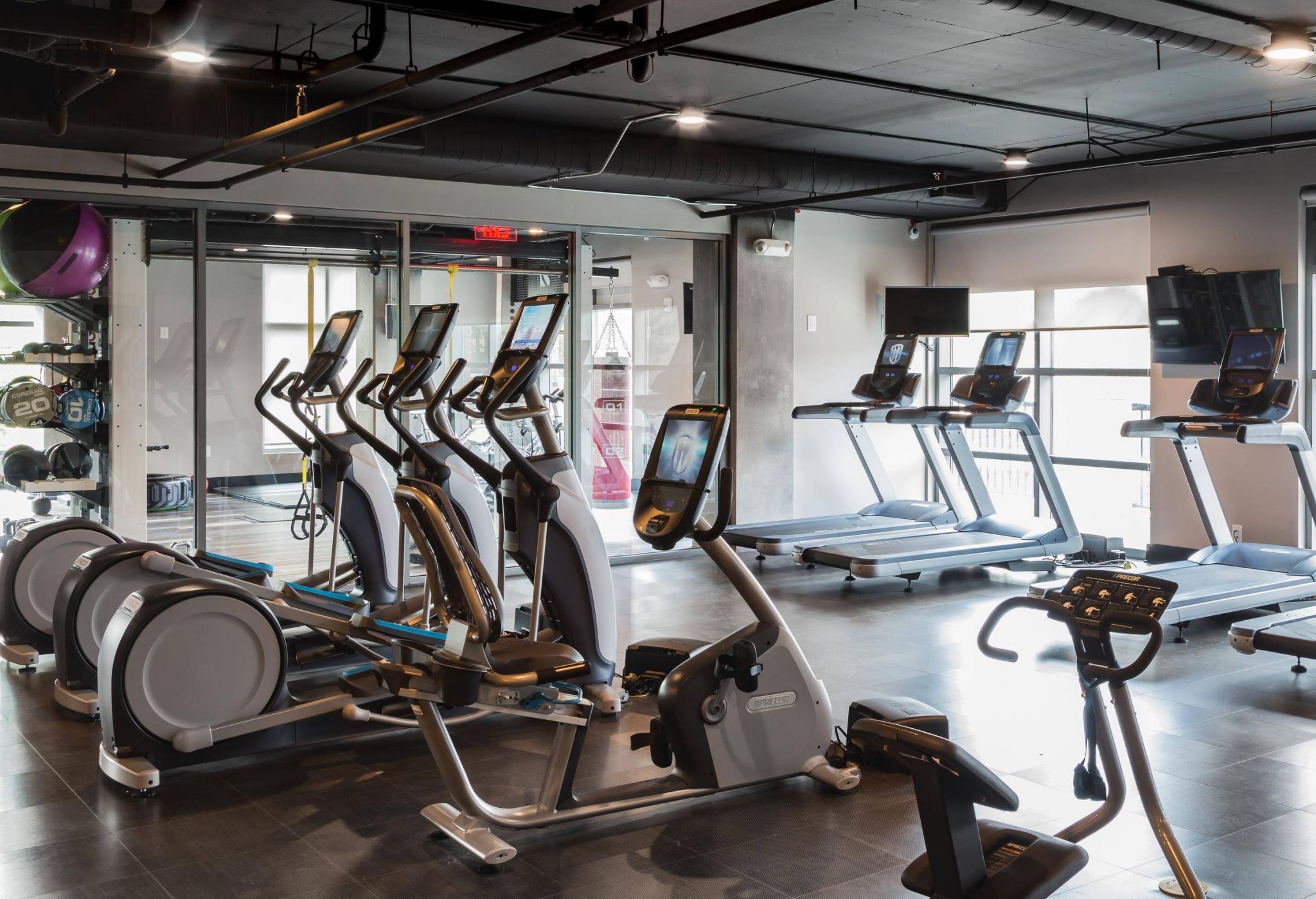 Modern gym with treadmills, elliptical machines, and cardio equipment in a bright, spacious room.