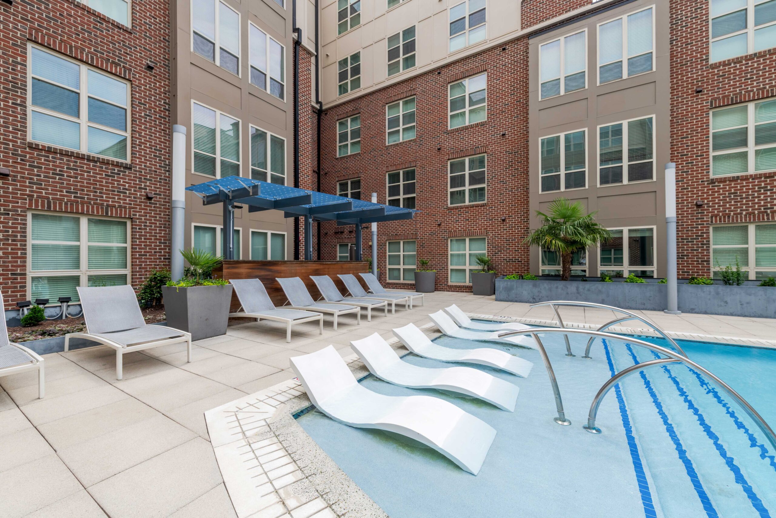 Modern apartment courtyard at Carolina Square with pool, lounge chairs, and shaded seating—ideal for UNC sophomores seeking on-campus housing.