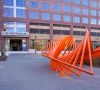 Bright orange abstract sculpture outside a modern office building labeled "123 West Franklin.