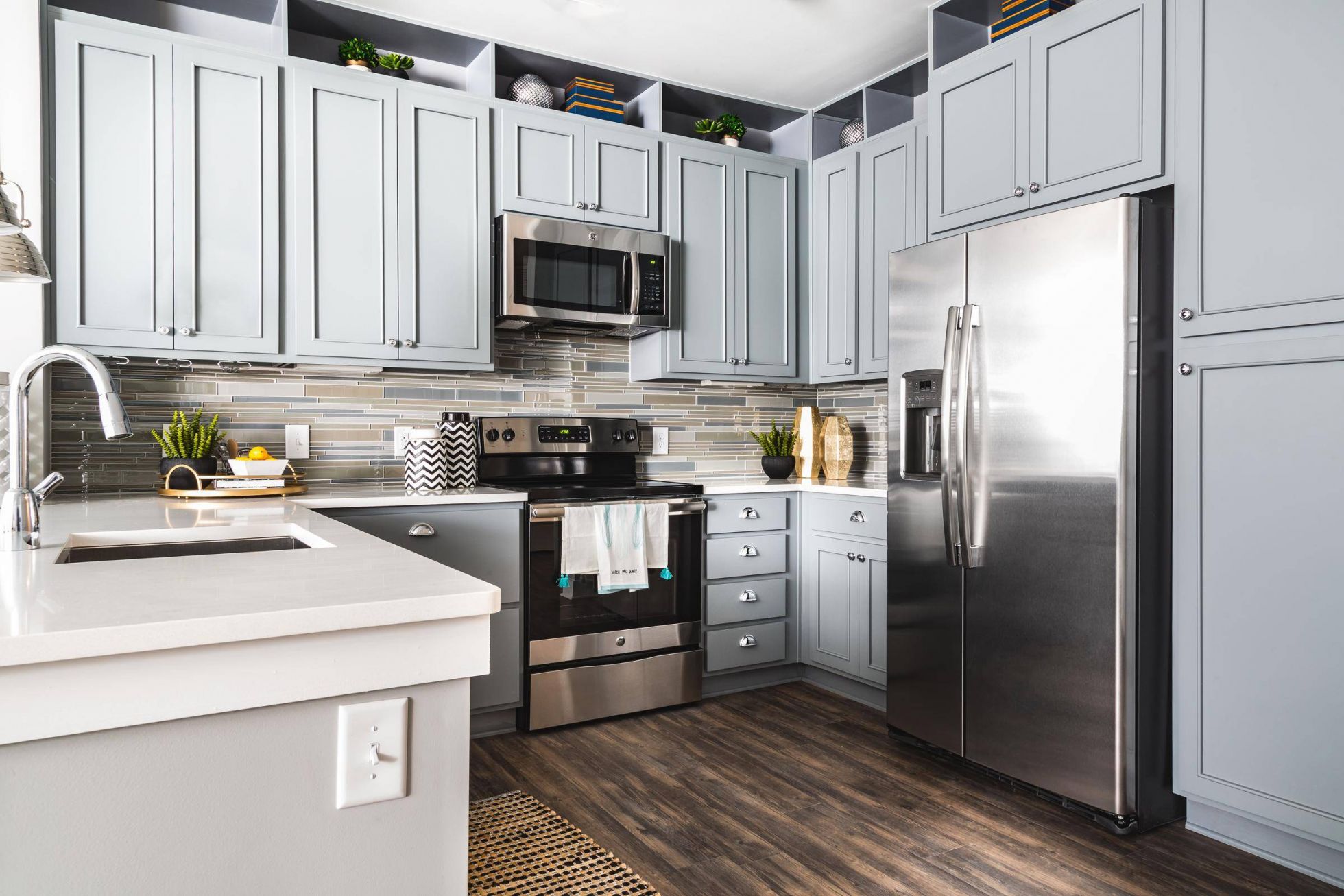 Modern kitchen with light gray cabinets, stainless steel appliances, and a tile backsplash.