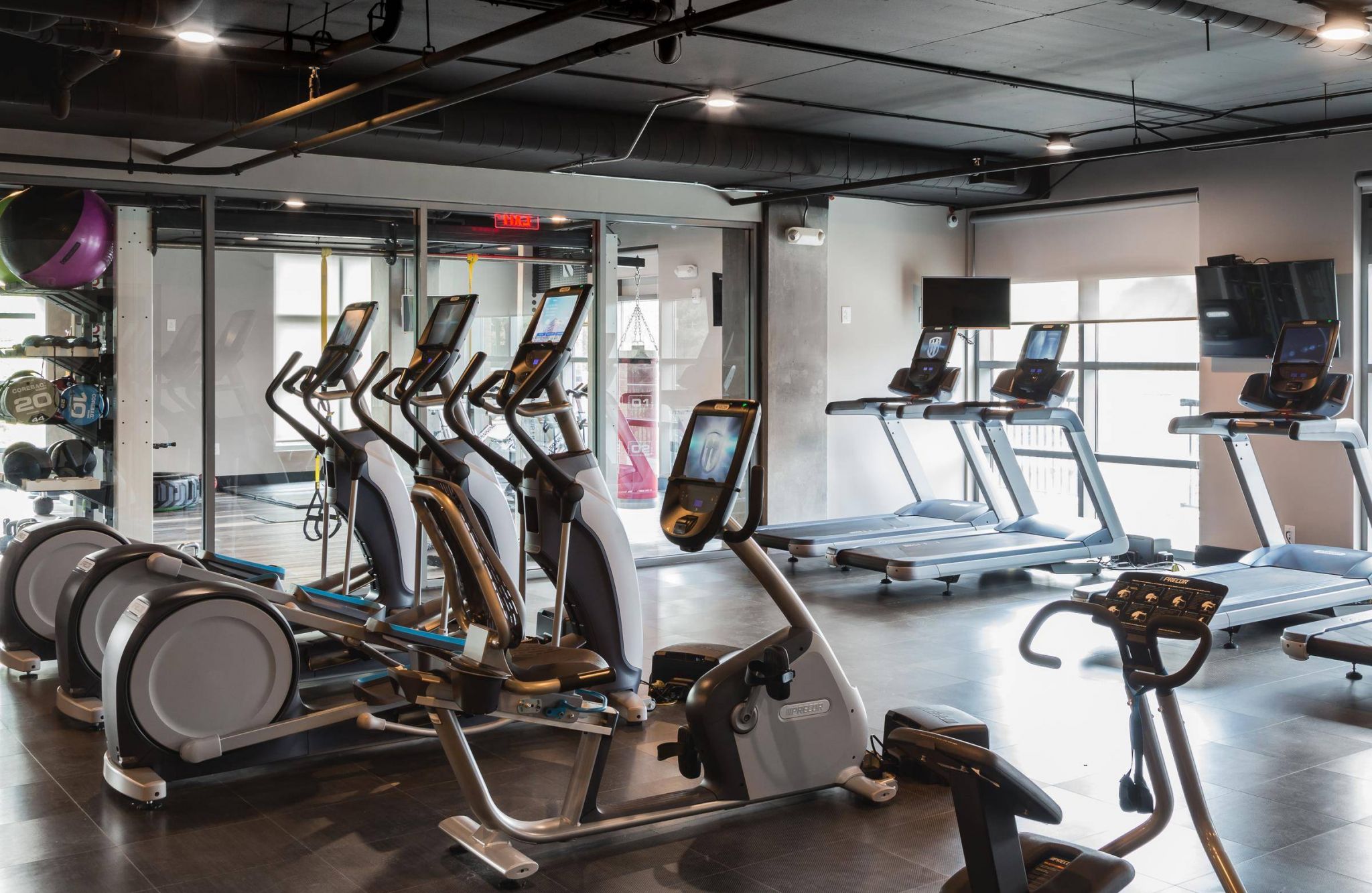 Modern gym with treadmills, elliptical machines, and cardio equipment in a bright, spacious room.
