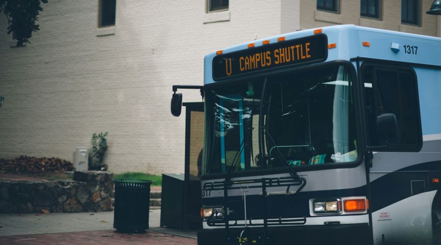 A campus shuttle bus is parked at a stop near Carolina Square, providing easy campus access for UNC students.