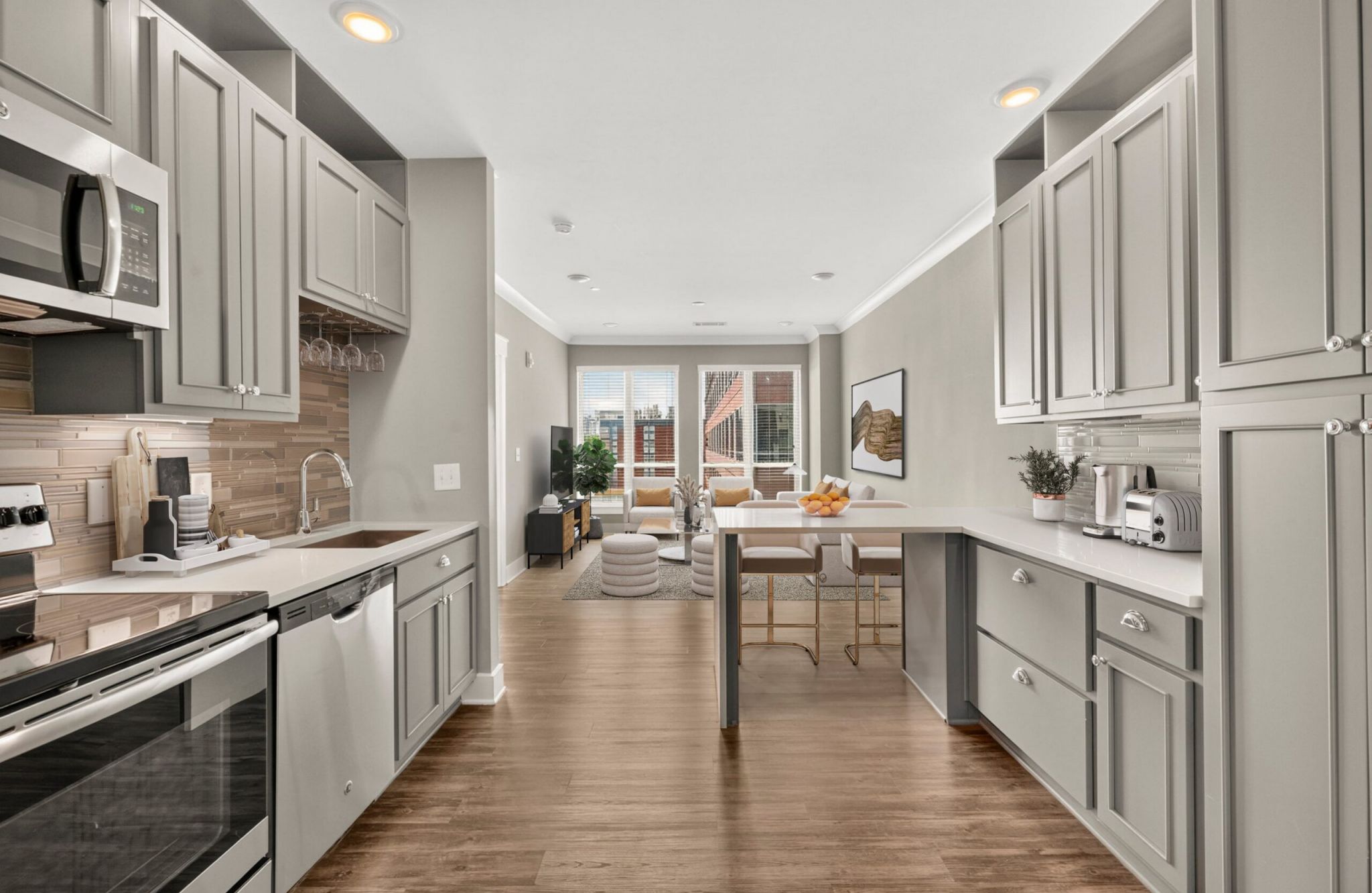 Luxury apartment kitchen with floating kitchen island, pendant lighting, ample cabinet storage, and built-in wine storage