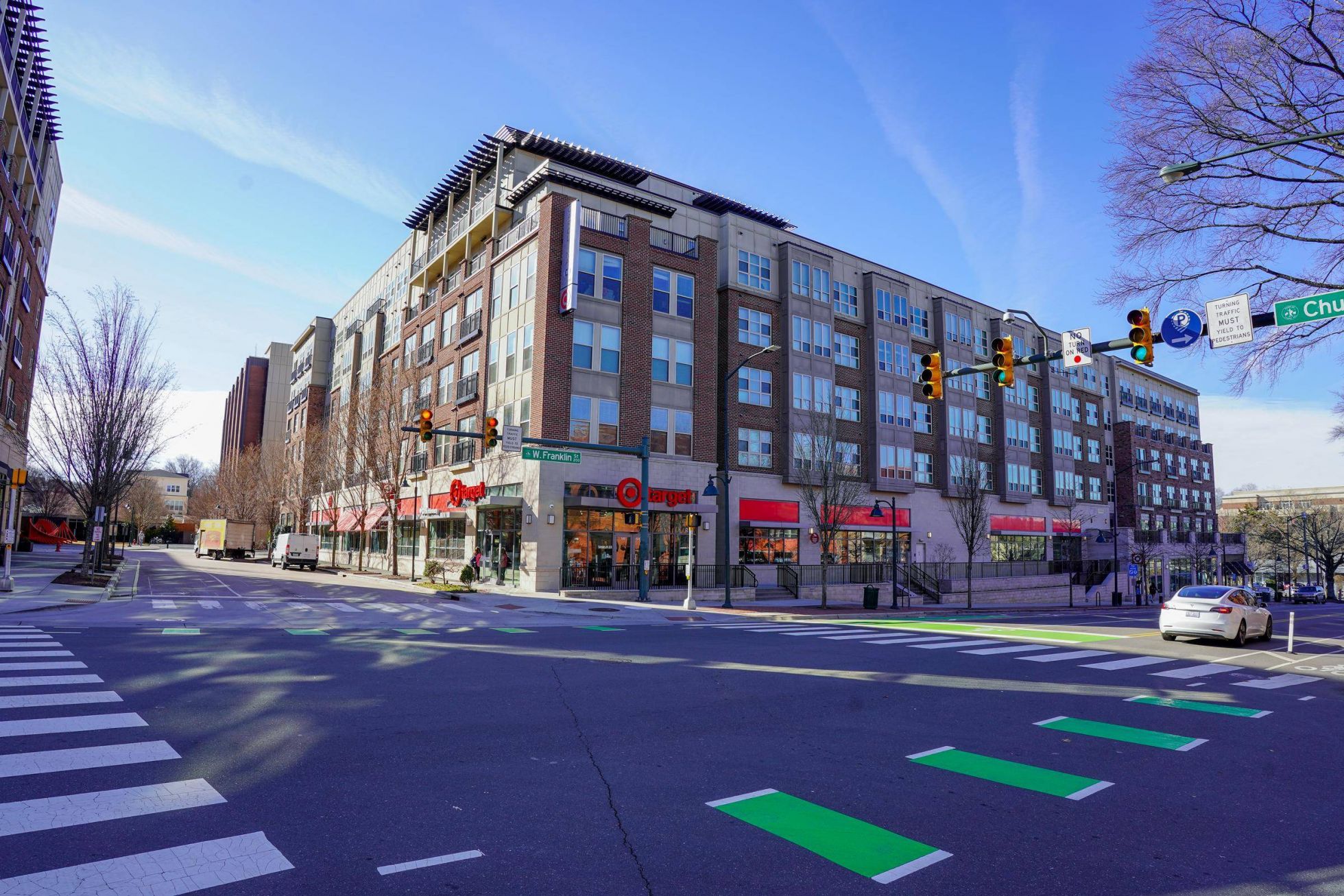A city intersection with crosswalks, a Target store, and apartments above under a clear blue sky at Carolina Square aparements
