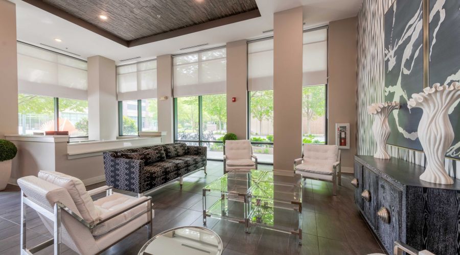 Modern lobby with large windows, stylish seating, glass tables, and decorative wall art and sculptures.